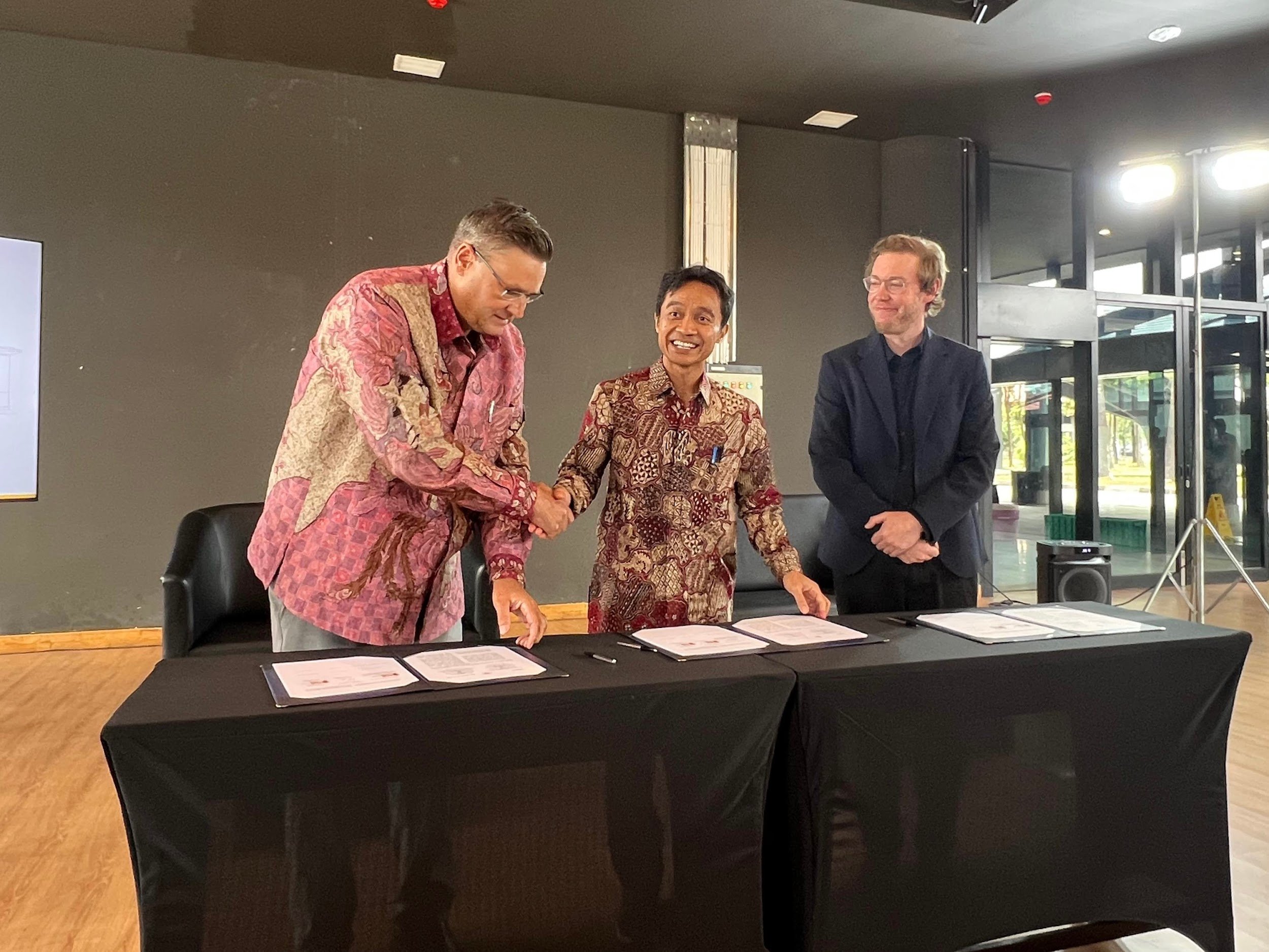 Scott Dykstra (right) signs the partnership into effect with representatives from Indomobil (left) and UGM (center).