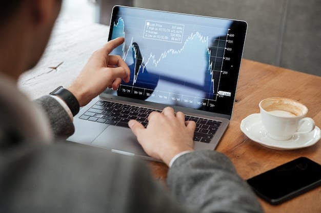 cropped image of businessman sitting by the table in cafe and analyzing indicators on laptop computer